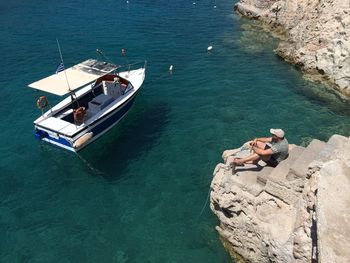 High angle view of man sitting on steps with boat moored in sea