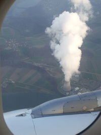 Close-up of airplane flying over landscape against sky