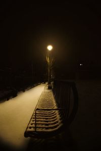Empty footbridge over illuminated street lights at night