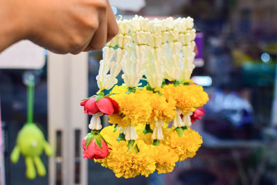 Close-up of hand holding floral garlands