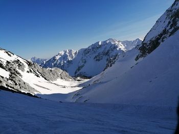 Scenic view of snowcapped mountains against clear blue sky