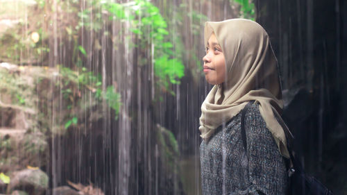 Side view of young woman standing in forest