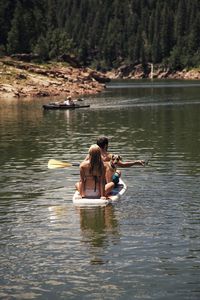 People with dog paddleboarding on lake