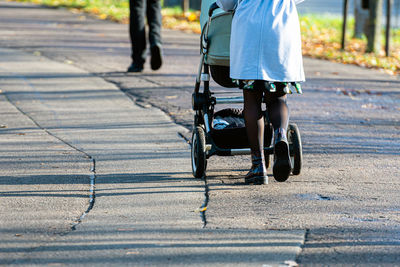Low section of woman walking with baby stroller on road