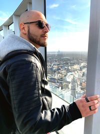 Bald man looking at city through window