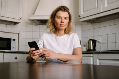 Young woman using mobile phone while sitting at home