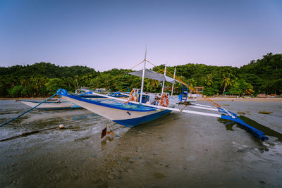 Sailboats moored on beach against clear blue sky