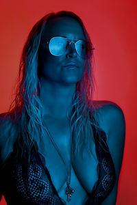 Woman wearing sunglasses against red background