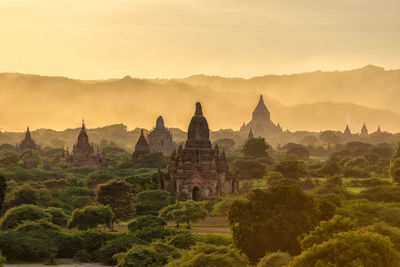 Temple by building against sky during sunset