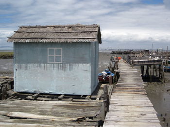 Wooden pier by sea against sky