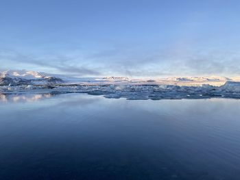 Scenic view of lake by snowcapped mountains against sky