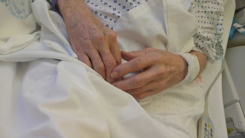 Midsection of senior woman lying on bed in hospital