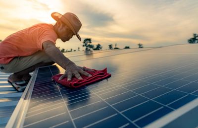 Man cleaning solar panel on roof. solar panel or photovoltaic module maintenance. sustainable.