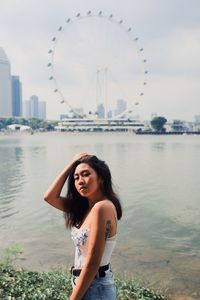 Fashionable young woman standing against sea and urban skyline