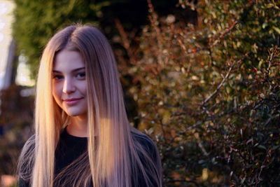 Close-up portrait of beautiful young woman standing against plants