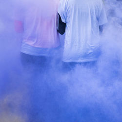 Low section of people walking amidst purple powder paint during holi