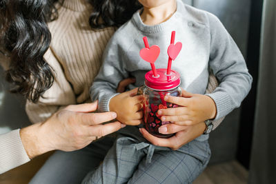 A glass smoothie mug with two tubes with hearts in the hands of a young son. valentine's day 