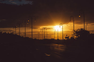 Silhouette street against sky during sunset