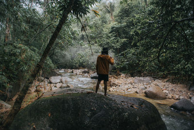 Rear view of man walking on rocks in forest