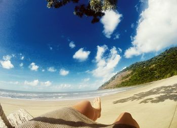 Low section of person relaxing on sand at beach