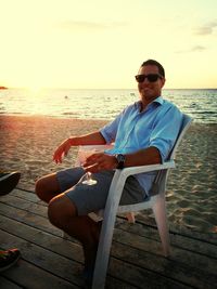 Woman sitting on beach at sunset