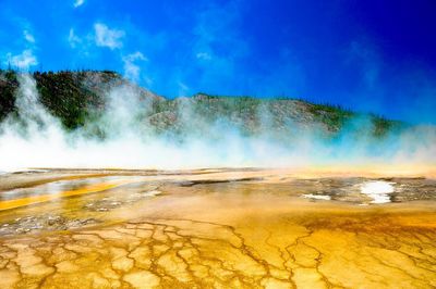 Scenic view of hot spring against clear blue sky