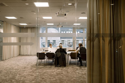 Male and female colleagues attending conference meeting in board room at office