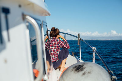 Rear view of woman sitting on boat sailing in sea