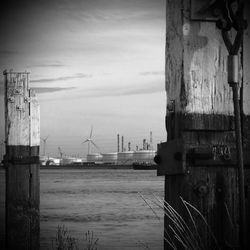 Wooden post on pier by sea against sky