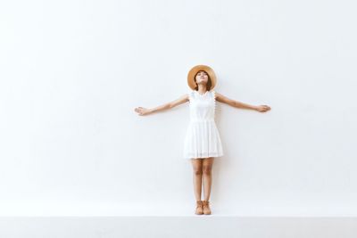 Portrait of young woman standing against white background