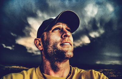 Portrait of young man looking away against sky