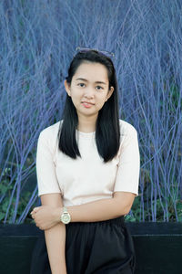 Portrait of young woman using mobile phone while sitting on field