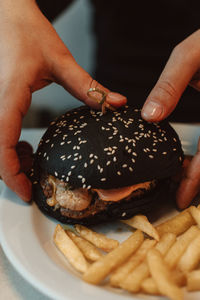 Male hands holding a beef burger with a black bun in a cafe. american delicious lunch