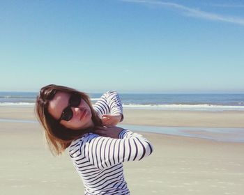 Portrait of woman in sunglasses at beach against sky