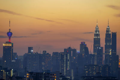 Illuminated buildings against sky during sunset