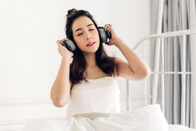 Beautiful young woman sitting on bed