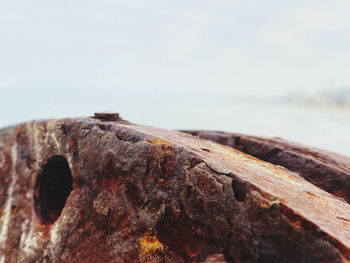 Close-up of rusty metal on rock against sky