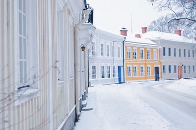 Snow covered street amidst buildings in city