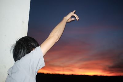 Rear view of boy standing against sky