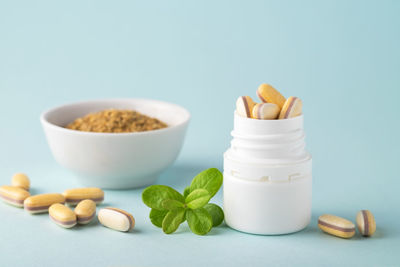 Vitamins and herbal supplements in jars with a green plant.