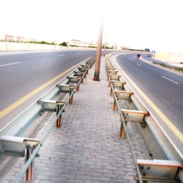 the way forward, diminishing perspective, vanishing point, transportation, railing, empty, clear sky, long, built structure, sky, day, architecture, railroad track, outdoors, sunlight, road marking, narrow, no people, road, absence