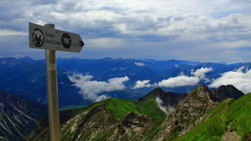 Road sign by mountains against sky