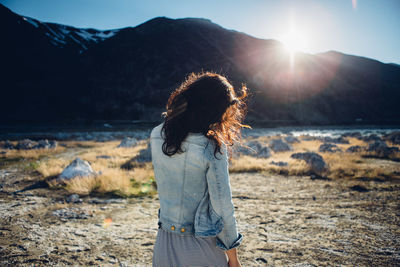 Woman standing by tree against sky during sunset