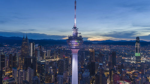 Illuminated modern buildings in city against sky