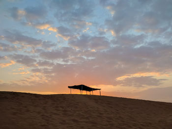Shelter structure on top of sand dune in the sunset