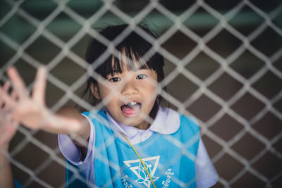 Portrait of cute girl standing against fence