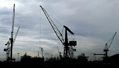 Low angle view of cranes against sky