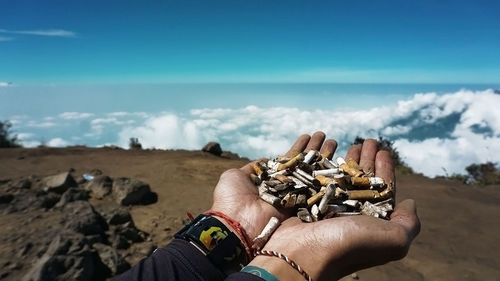 Midsection of hands on sand at beach against sky