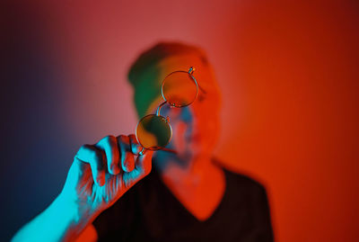Close-up of hand holding orange against wall