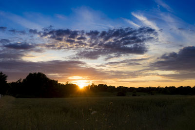 Scenic view of silhouette field against sky at sunset